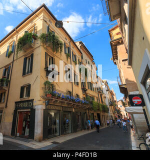 Verona, Italien - 26. Mai 2017: Haus mit Geschäften und blaue Blumen auf einem Balkon in der Fußgängerzone von Verona, Italien Stockfoto