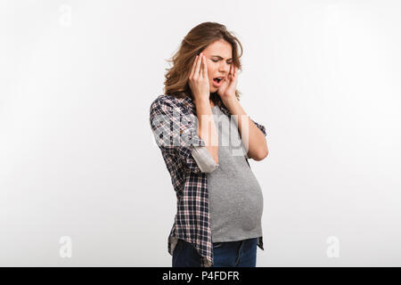 Portrait von jungen schwangeren Frau mit Kopfschmerzen isoliert auf Grau Stockfoto