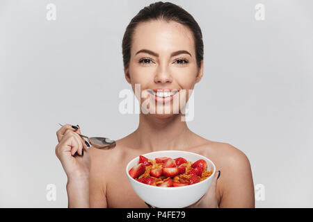 Attraktive junge Frau isst Müsli Frühstück mit Erdbeeren isoliert auf weißem Stockfoto