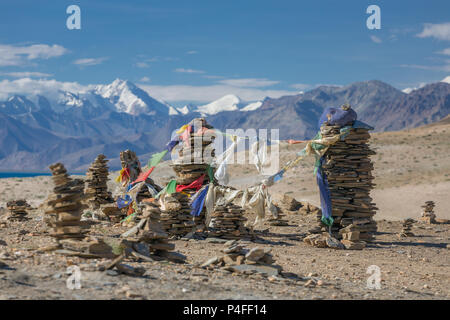 Kleine buddhistische Stupas, die aus grauen Steinen mit buddhistischer Gebetsfahnen an der Spitze des Hügels auf dem Hintergrund einer hohen Himalaya und Blue s Stockfoto