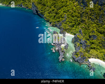 Antenne drone Blick auf die Boote über eine kristallklare Korallenriffs und versteckten Sandstrand umgeben von Felsen (Hidden Beach, Palawan) Stockfoto