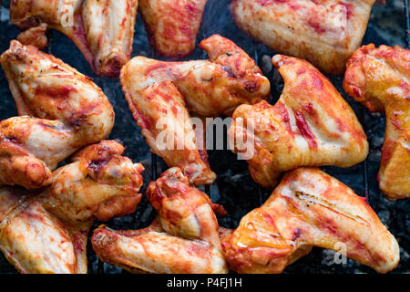 Scharf marinierte Hähnchenflügel grillen an einem sommerlichen Barbecue mit heißen Flammen in der Nähe zu sehen. Stockfoto