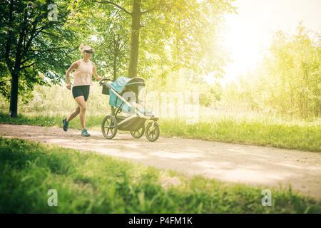 Läuft eine Frau mit Kinderwagen geniessen Sommertag im Park. Joggen oder Walken supermom, aktive Familie mit Baby Jogger. Stockfoto