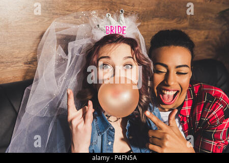 Verlobter blasen Bubble Gum und Rock mit glücklich afrikanische amerikanische Freund in der Nähe von Stockfoto