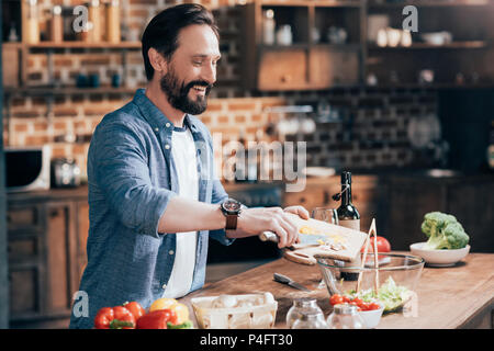 Lächelnd bärtiger Mann Kochen Gemüse Salat in der Küche Stockfoto