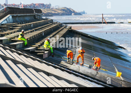 Arbeiter von Balfour Beatty carryout Ufermauer Reparaturen an der Küstenverteidigung Welle Reflektionswand. Ingenieure einer Baufirma, die von lokalen Räten beschuldigt wird, das vierjährige Programm in Blackpool zu verpfuschen, das 27,1 Mio. £kostete, nachdem sich zwischen den Abschnitten der Betonmeerwand aufgrund von Wasserschäden und Paneelen, die Erosionszeichen zeigten, Lücken gebildet hatten. Balfour Beatty sagte, es sei bekannt, dass Wasser aus einer Fuge zwischen Betonabschnitten in Richtung des nördlichen Endes der Anchorsholme Fleetwood Flutverteidigung austritt. Stockfoto