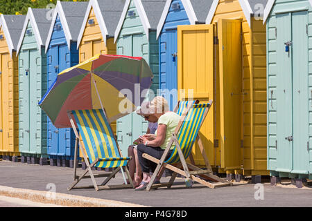 Bournemouth, Dorset, Großbritannien. Am 22. Juni 2018. UK Wetter: schön warmen sonnigen Tag in Bournemouth Strände als Besucher gehen zum Meer den Sonnenschein zu machen, wie die Prognose ist für Temperaturen weiter zu erhöhen. Zwei Frauen in Liegestühlen unter einem Sonnenschirm an der Promenade am Strand Hütten. Credit: Carolyn Jenkins/Alamy leben Nachrichten Stockfoto