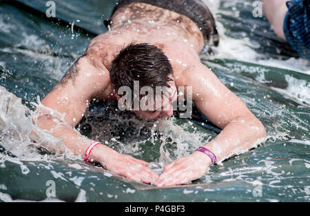 22 Juni 2018, Deutschland, Scheeßel: Niklas springt auf einer Wasserrutsche im Campingplatz der Hurricane Festival. 65.000 Besucher zum Open Air Festival vom 22. bis zum 24. Juni. Foto: Hauke-Christian Dittrich/dpa Stockfoto