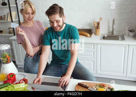 Vegan Paar mit Laptop Kauf von Waren online zusammen in der Küche zu Hause. Stockfoto