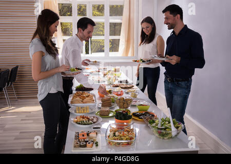 Glückliche junge Freunde und köstliches Essen serviert auf Tisch Stockfoto