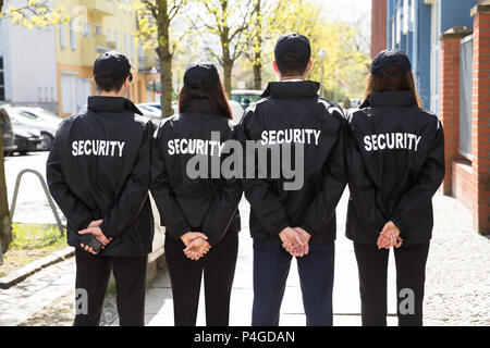 Ansicht der Rückseite des Security Guards mit den Händen hinter dem Rücken in einer Reihe Stockfoto