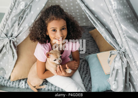 Ansicht von oben wenig lächelnde african american Kid mit Chihuahua Hund im Tipi zu Hause Stockfoto