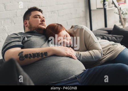 Freund und Größe plus Freundin liegen und schlafen auf dem Sofa zu Hause Stockfoto