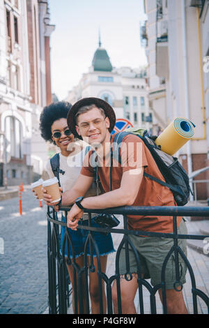 Glückliche junge interracial Paare von Reisenden mit Papier Tassen Kaffee Stockfoto