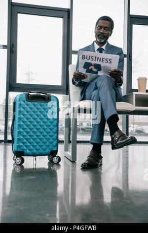 Im mittleren Alter Geschäftsmann lesen Zeitung im Flughafen Stockfoto
