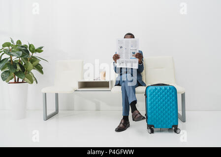 Afrikanische amerikanische Geschäftsmann im Wartezimmer sitzen und Zeitung lesen Stockfoto