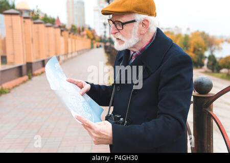 Bärtige ältere Mann in der Kappe an Karte suchen Stockfoto