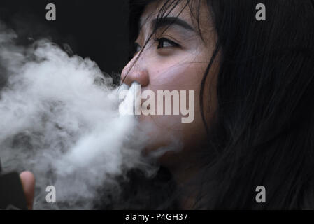 Eine Frau für ein Foto posieren, während vaping während eine elektronische Zigarette Messe in Jakarta, Indonesien. Stockfoto