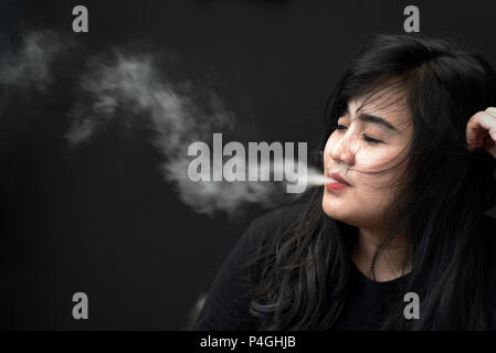 Eine Frau für ein Foto posieren, während vaping während eine elektronische Zigarette Messe in Jakarta, Indonesien. Stockfoto
