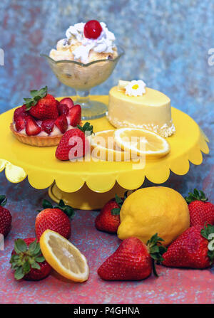 Süß und bunt Desserts für das Frühjahr: Eisbecher, Erdbeer und Zitrone Custard tart, glasierten Kuchen mit weißer Schokolade curl Stockfoto