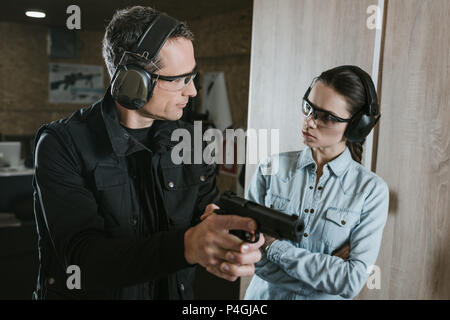 Männliche Kursleiter Beschreibung Gewehr zu weiblichen Klienten in Shooting Gallery Stockfoto