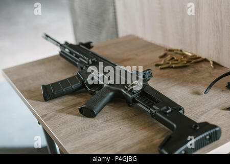 Schwarz Gewehr mit Kugeln auf hölzernen Tisch in Schießstand Stockfoto