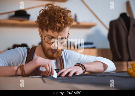 Junge Bartgeier Fashion Designer arbeiten mit Gewebe an Workshop konzentriert Stockfoto