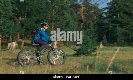 Fat bike auch fatbike oder Fat Tire Bike im Sommer Reiten im Wald. Der Kerl fährt Fahrrad zwischen Bäumen und Stümpfe. Er überwindet einige obstac Stockfoto