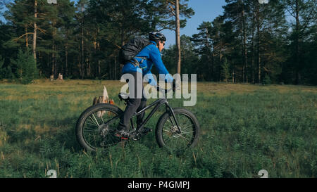 Fat bike auch fatbike oder Fat Tire Bike im Sommer Reiten im Wald. Der Kerl fährt Fahrrad zwischen Bäumen und Stümpfe. Er überwindet einige obstac Stockfoto