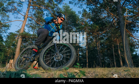 Fat bike auch fatbike oder Fat Tire Bike im Sommer Reiten im Wald. Der Kerl, Fahrten mit dem Fahrrad auf den Waldboden. Es geht in einer kontrollierten Sk Stockfoto