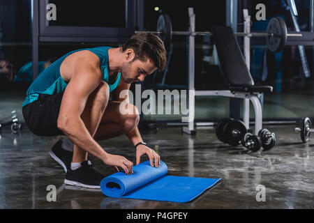 Sportler rollt Yoga Matte im Sportzentrum Stockfoto