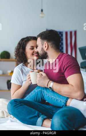 Seitenansicht des Jungen küssen paar hält Cups Stockfoto