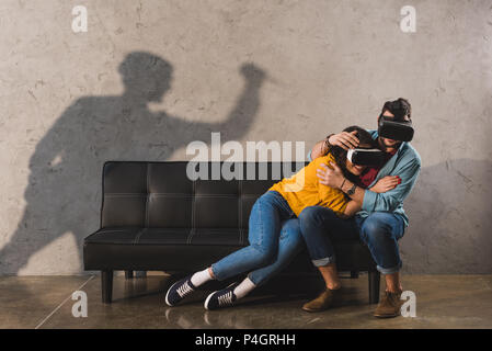 Schatten der Mann mit Messer und Paar in virtual reality Headset auf der Couch Stockfoto