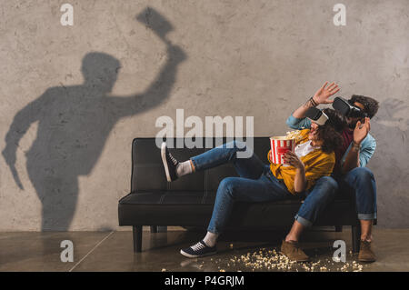 Schatten der Mann mit Axt und Angst Paar mit Popcorn mit Virtual reality Headset Stockfoto
