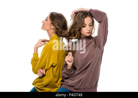 Attraktive junge Zwillinge mit Haar in einem Zopf isoliert auf weißem Stockfoto