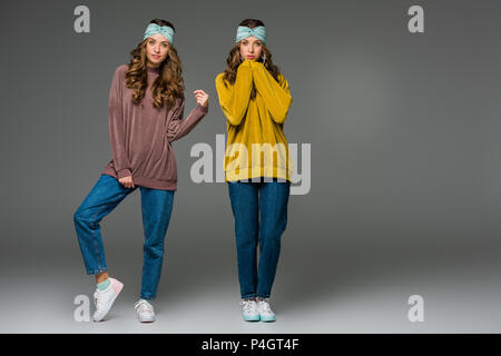 Attraktive junge Zwillinge in Pullover an Kamera suchen auf Grau Stockfoto