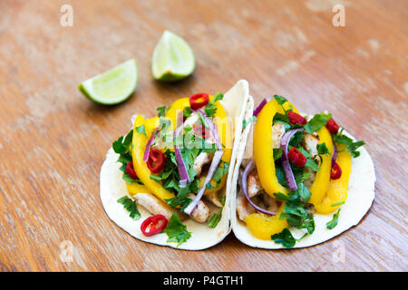 Tacos mit gegrilltem Hähnchenbrustfilet, frisches Gemüse und Kalk. Rustikal Hintergrund. Seitenansicht, Nahaufnahme. Stockfoto