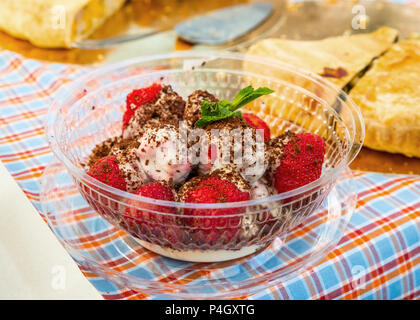 Frische Erdbeeren mit Schokolade überzogene Eis mit einem minzeblatt auf dem Tisch mit hausgemachten Kuchen Stockfoto