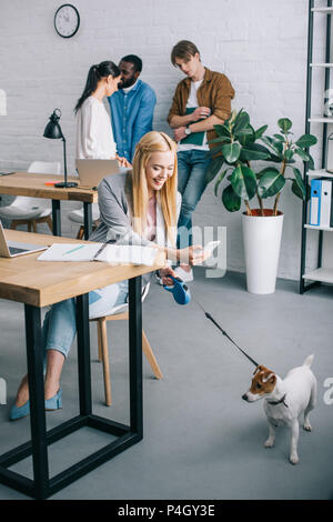 Lächeln, Geschäftsfrau, der Hund an der Leine und Mitarbeiter in Sitzung hinter in modernen Büro Stockfoto