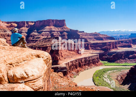 Von Schwanenhälse Blick entlang der White Rim Road, ein Mann, der Blick auf den Colorado River Schwanenhals, Shafer Trail, Sandstein Klippen und Berge in der Ferne. Stockfoto