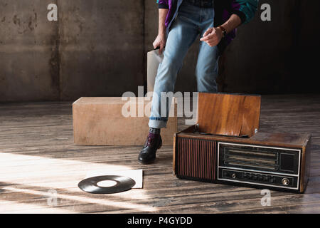 7/8 Schuß von Mann in vintage Regenjacke mit vinyl Plattenspieler Stockfoto