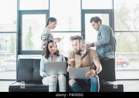 Diverse Business Team arbeiten auf Laptops und diskutieren Projekt in hellen Arbeitsbereich Stockfoto