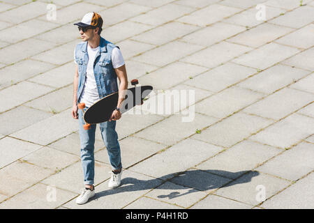 Hohe Betrachtungswinkel von gutaussehenden jungen Mann zu Fuß mit Skateboard in der Hand Stockfoto