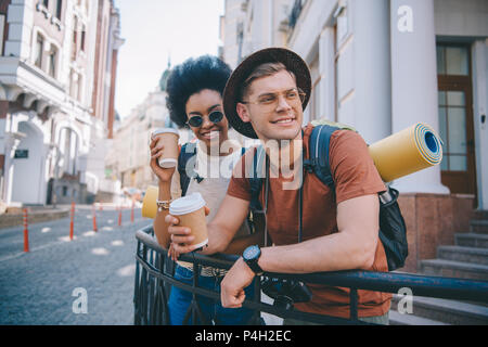 Lächelnd multikulturelles Paar Touristen stehend mit Einweg Tassen Kaffee Stockfoto