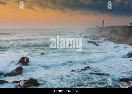 Sonnenuntergang am Point Arena Lighthouse, der in Nebel gehüllt ist, der von stürmischen Wellen, Salznebel und stürmischem Wetter in Point Arena, Kalifornien, erzeugt wird. Stockfoto