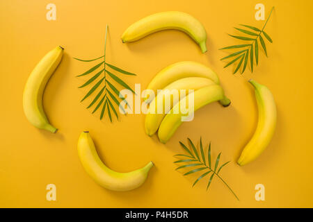 Bananen und Palmen Blätter auf leuchtenden gelben Hintergrund. Tropische Sommer Thema. Stockfoto