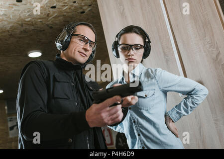 Männliche Kursleiter beschreibt Pistole zu weiblichen Klienten in Shooting Gallery Stockfoto