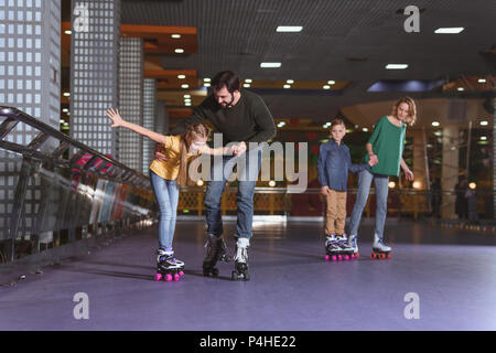 Eltern und Kinder Schlittschuhlaufen auf Roller Rink zusammen Stockfoto