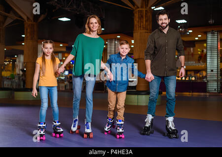 Eltern und Kinder gemeinsam Schlittschuhlaufen auf Roller Rink Stockfoto