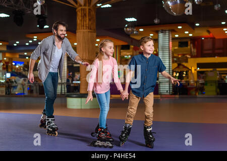 Vater und kleine Kinder skating zusammen auf Roller Rink Stockfoto